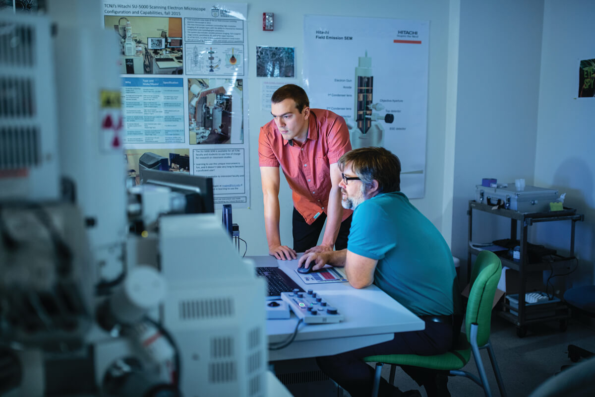 Magee (seated) and Lynn study wind-borne African dust samples under an electron scanning microscope.