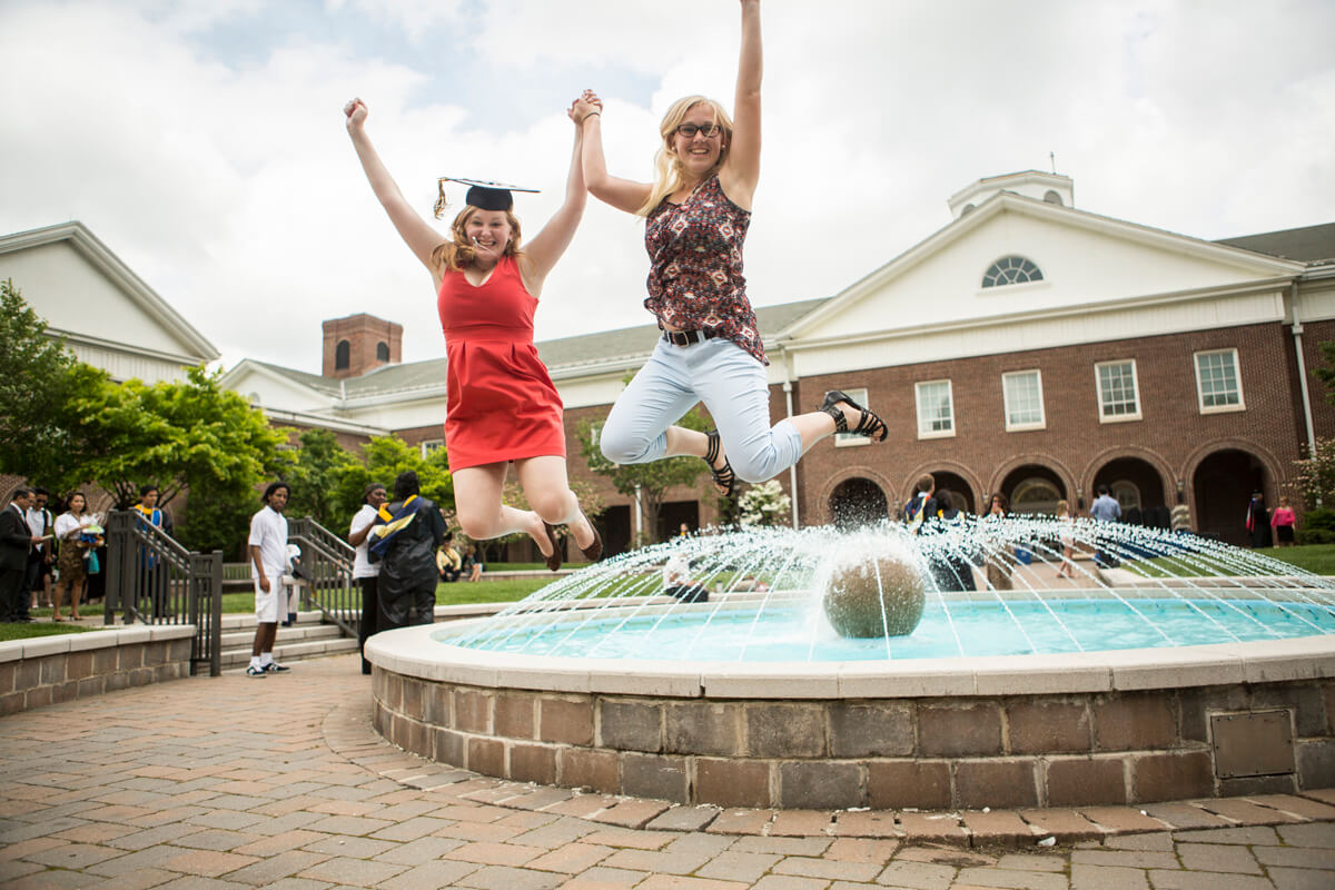 Two happy alum jump from the science fountain