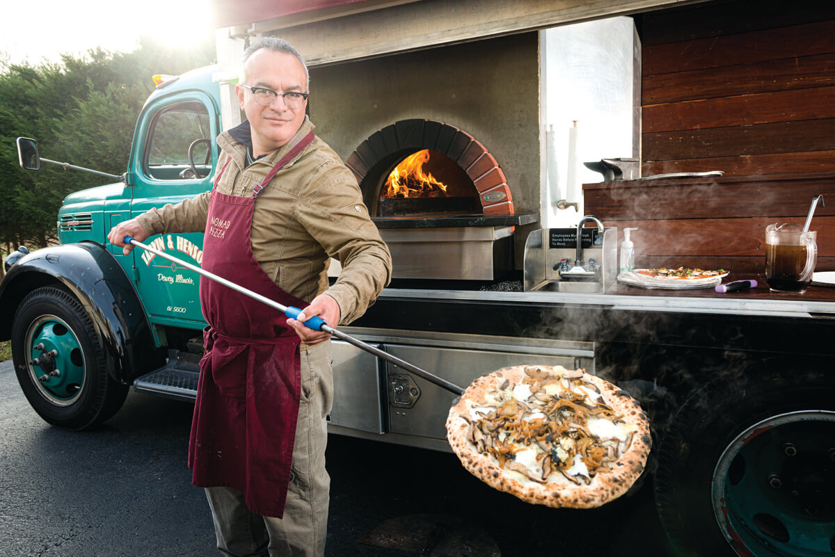 Nomad's Stalin Bedon makes pizza at a party on his tricked-out truck
