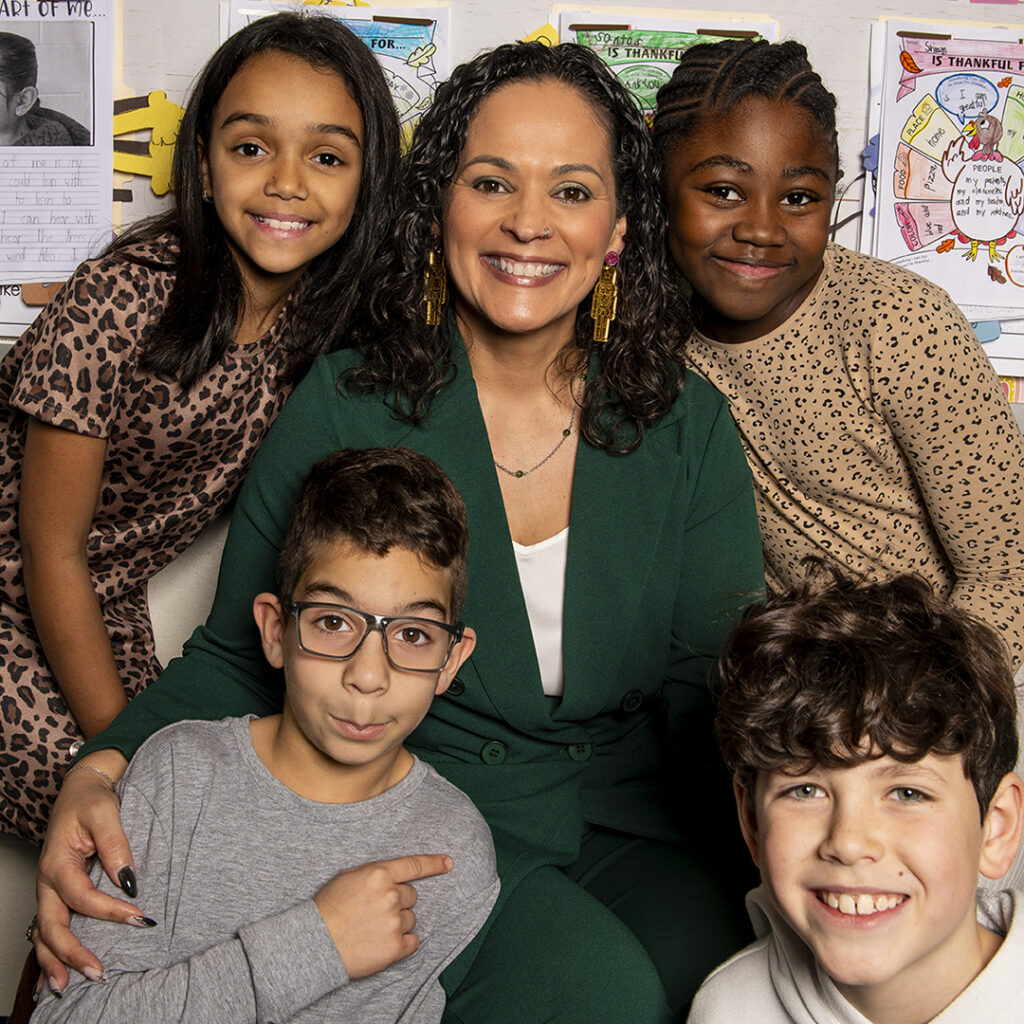 Teacher Marisol Gutierrez, sitting and surrounded by students