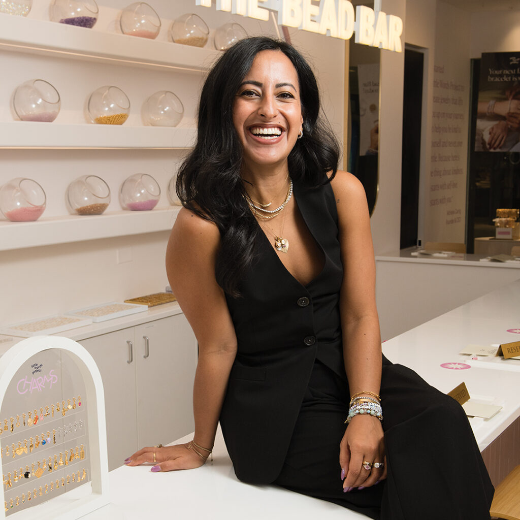 Founder of Little Words Project Adriana Carrig sits on counter in her store.